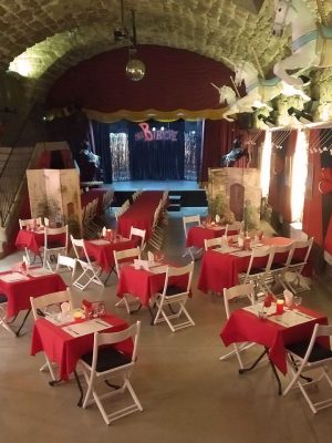 La salle voûtée du Cabaret Chez Bibiche et ses tables dressées face à la scène ; photo d’ambiance du menu.